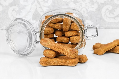 Homemade Dog Biscuits Spilling From A Glass Canister.