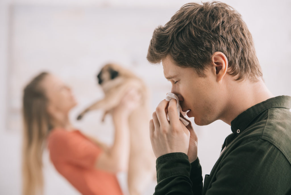 sneezing man with dog in the background